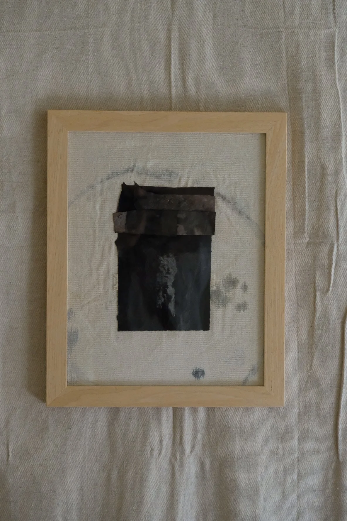 Framed 11 x 14 collage of layered near-black torn paper on pale canvas with grey rings