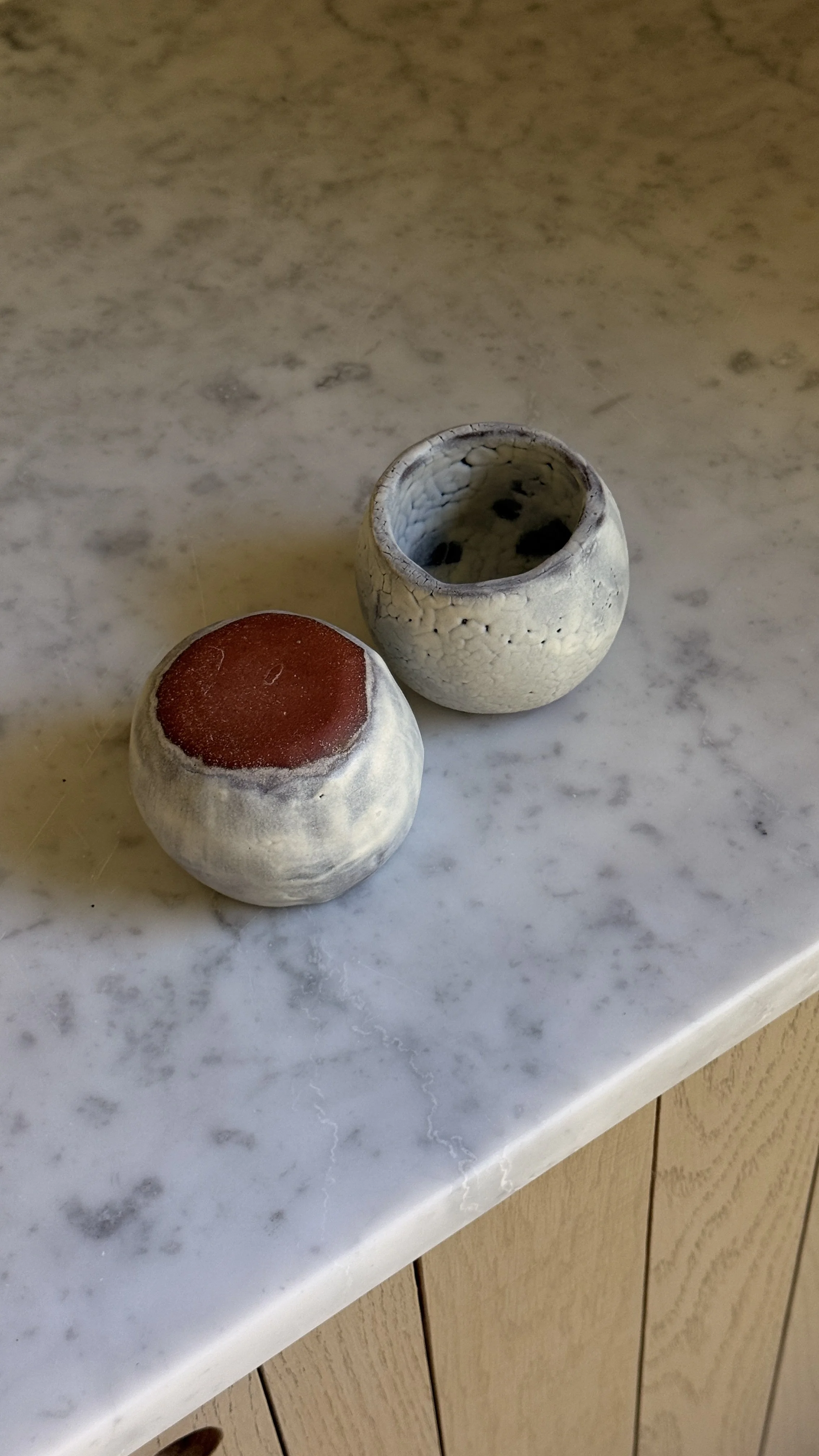 Set of two round handmade ceramic cups in pale blue-grey glaze, one smooth and clouded, the other with a fine white crackle texture