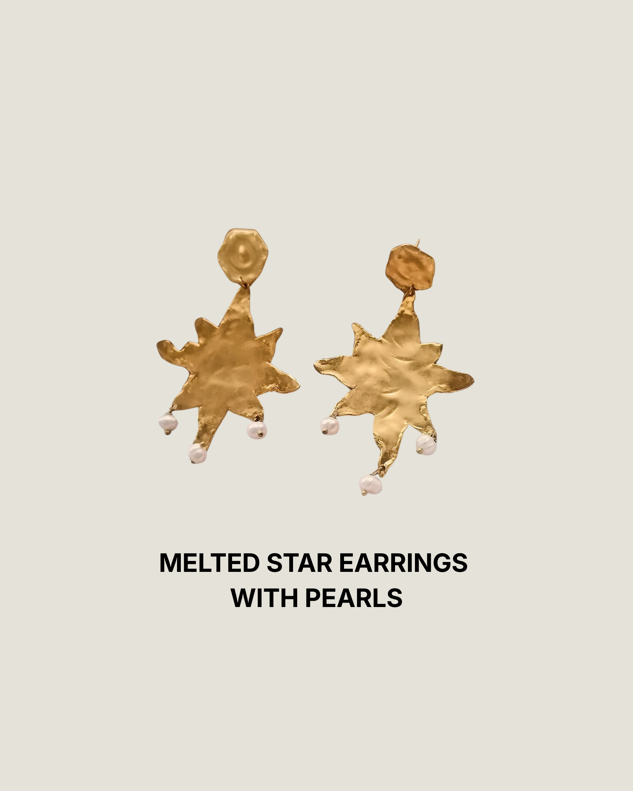 Gold melted star statement earrings with natural pearl drops on draped ivory fabric