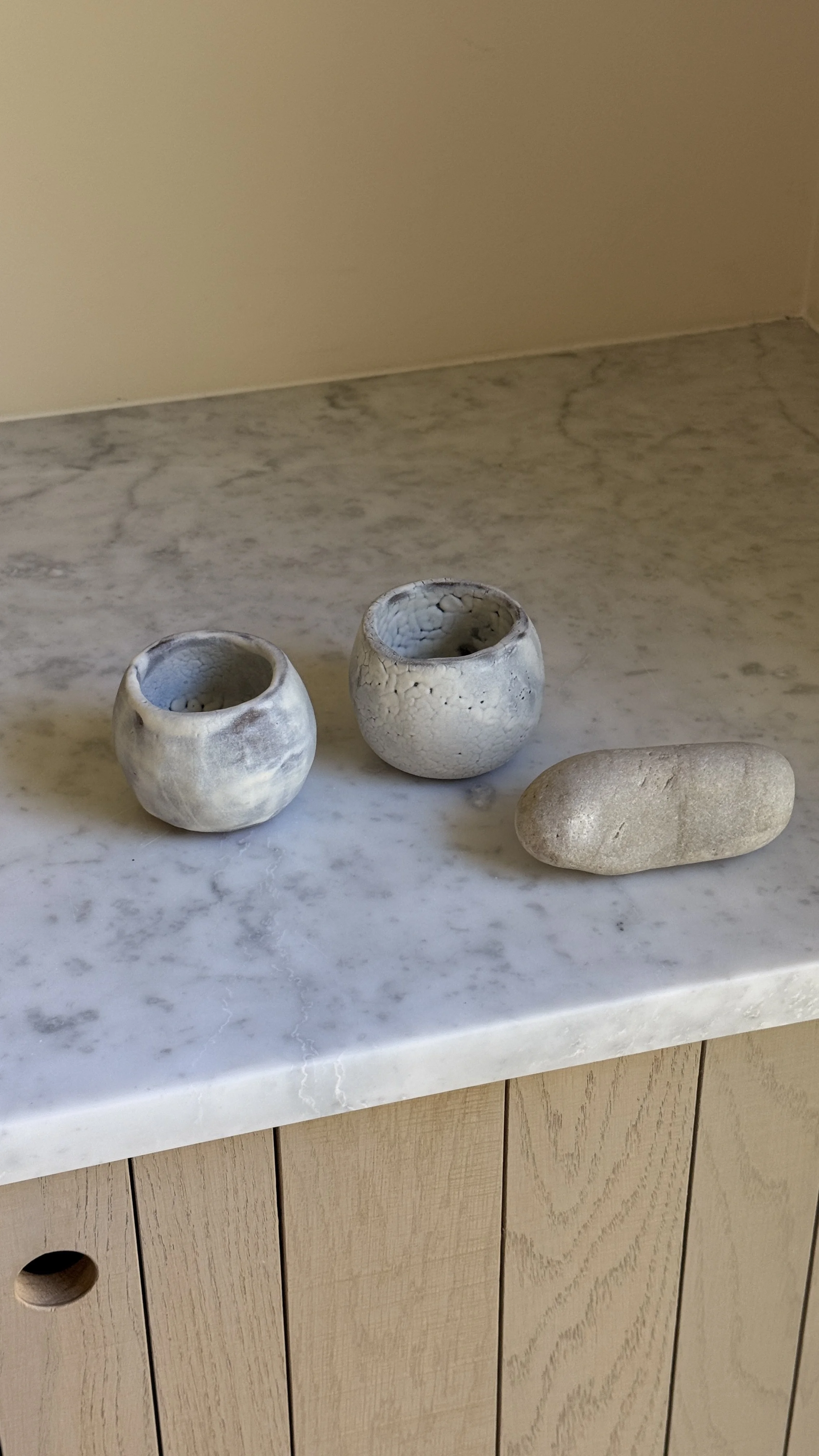 Set of two round handmade ceramic cups in pale blue-grey glaze, one smooth and clouded, the other with a fine white crackle texture