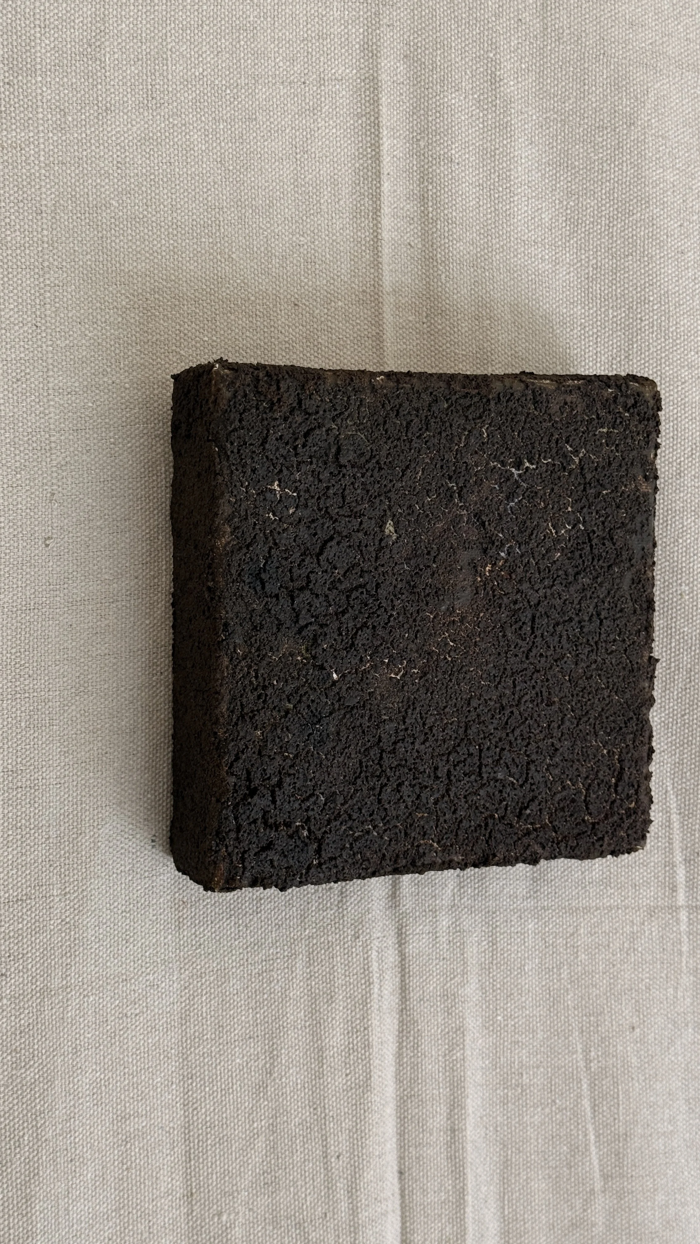 Small abstract artwork with a dense, cracked dark brown and black textured surface and faint pale veining, unframed 6x6 on linen