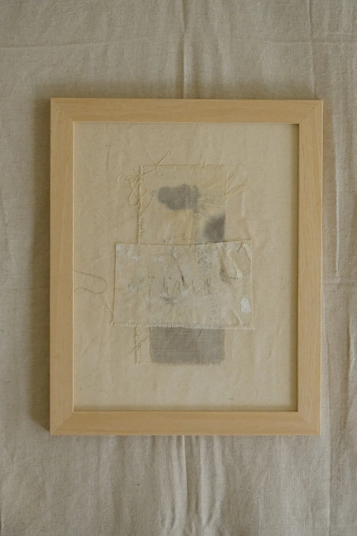 Framed 11 x 14 collage of layered canvas panels and a grey cloth patch with soft grey marks