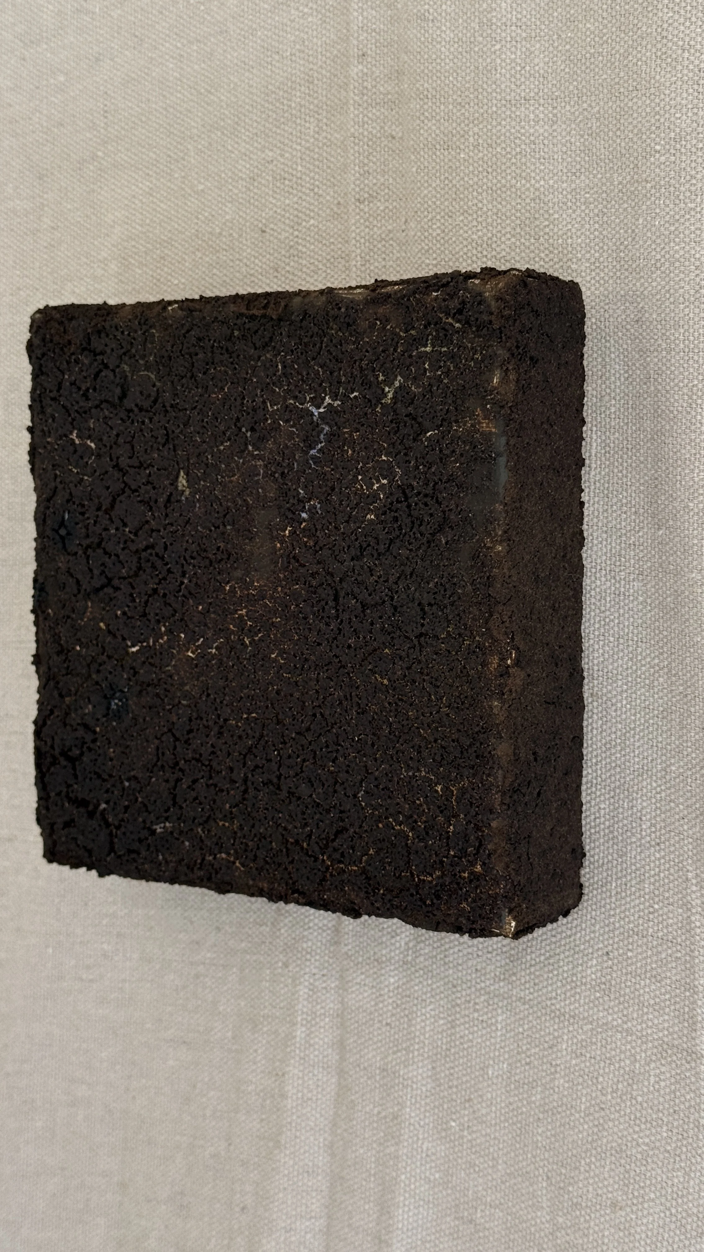 Small abstract artwork with a dense, cracked dark brown and black textured surface and faint pale veining, unframed 6x6 on linen