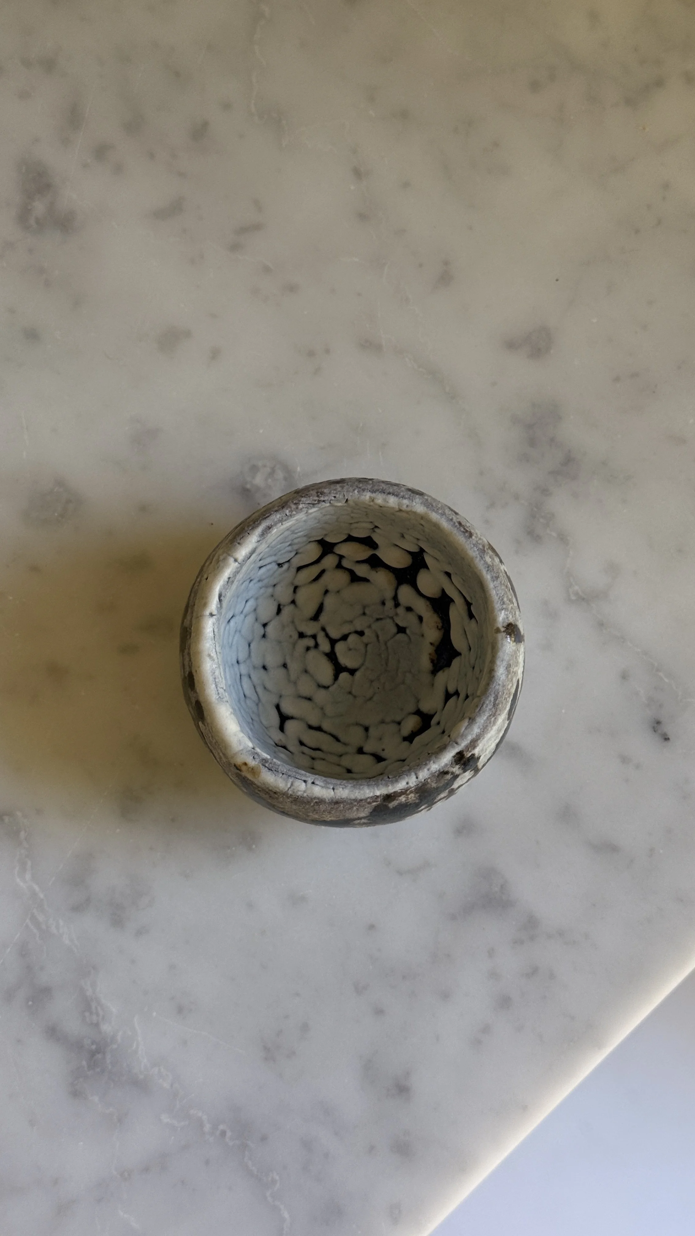 Round ceramic cup with white crackle glaze, black splatter and grid-like brush marks, and a small gold accent, pale crackled interior