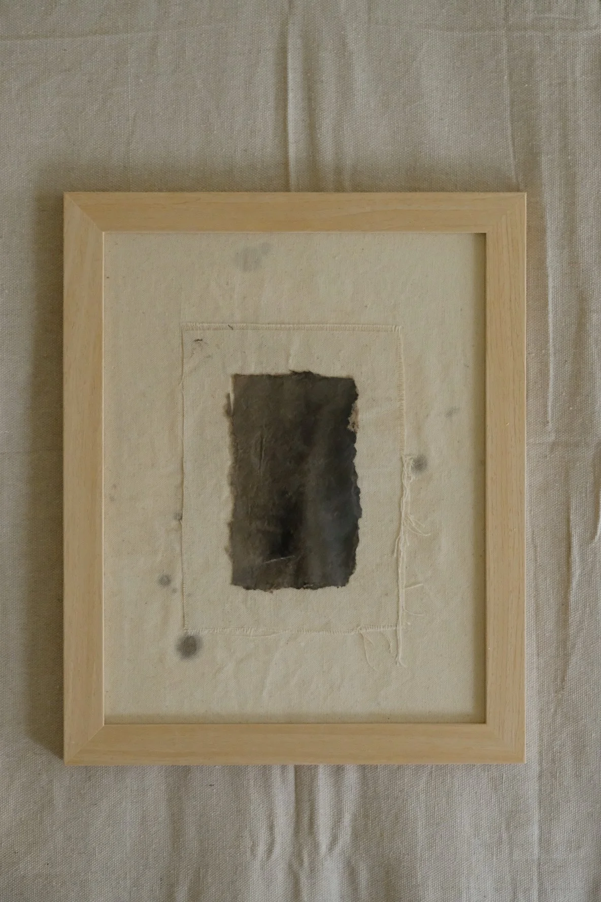 Framed 11 x 14 collage of torn dark paper on a stitched raw canvas panel