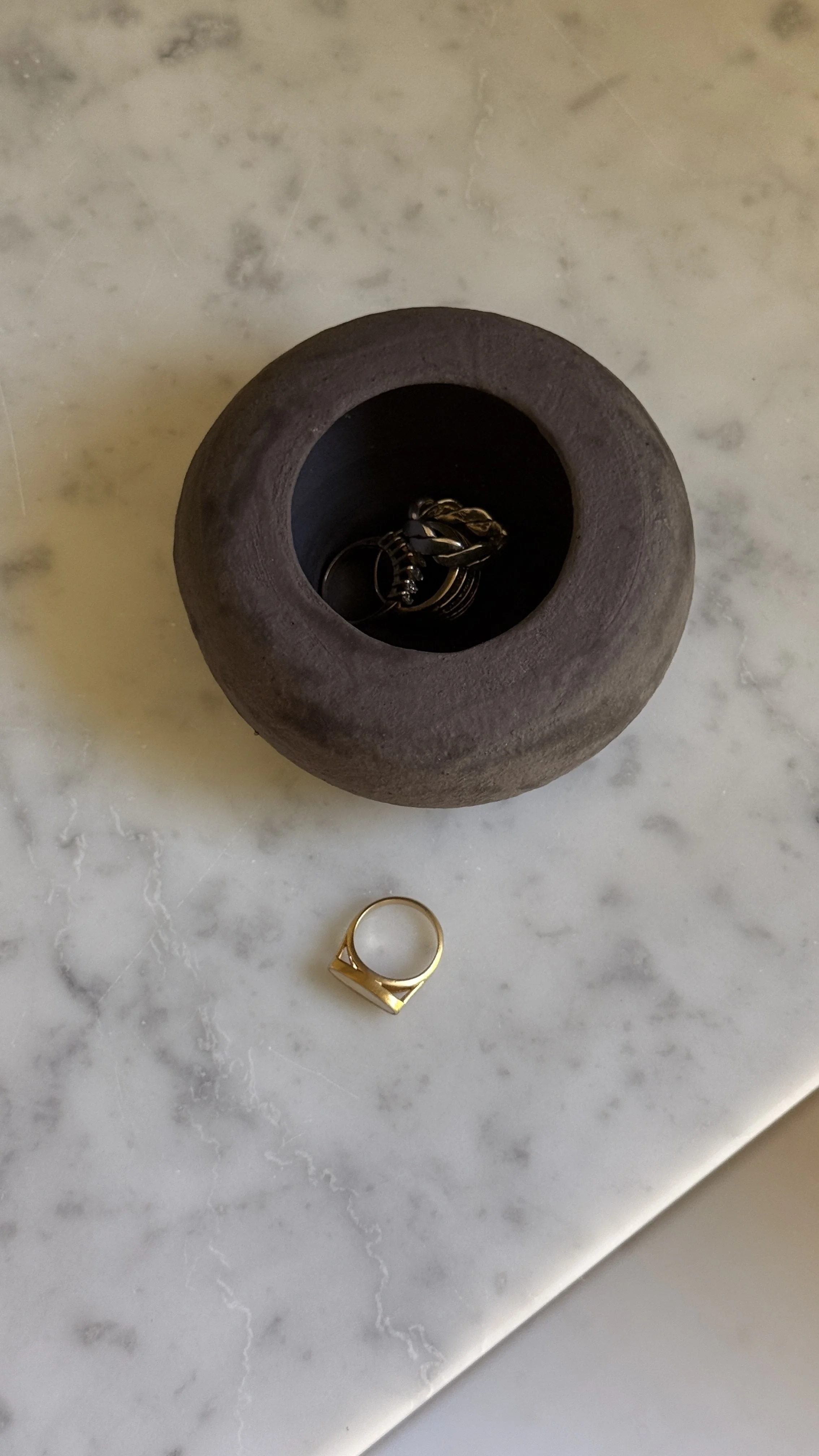Low rounded dark brown matte ceramic vessel shaped like a river stone with a small opening and black interior