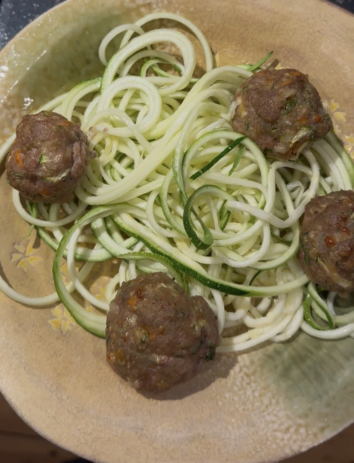 picture of meatballs in a bowl on top of zuchinni noodles