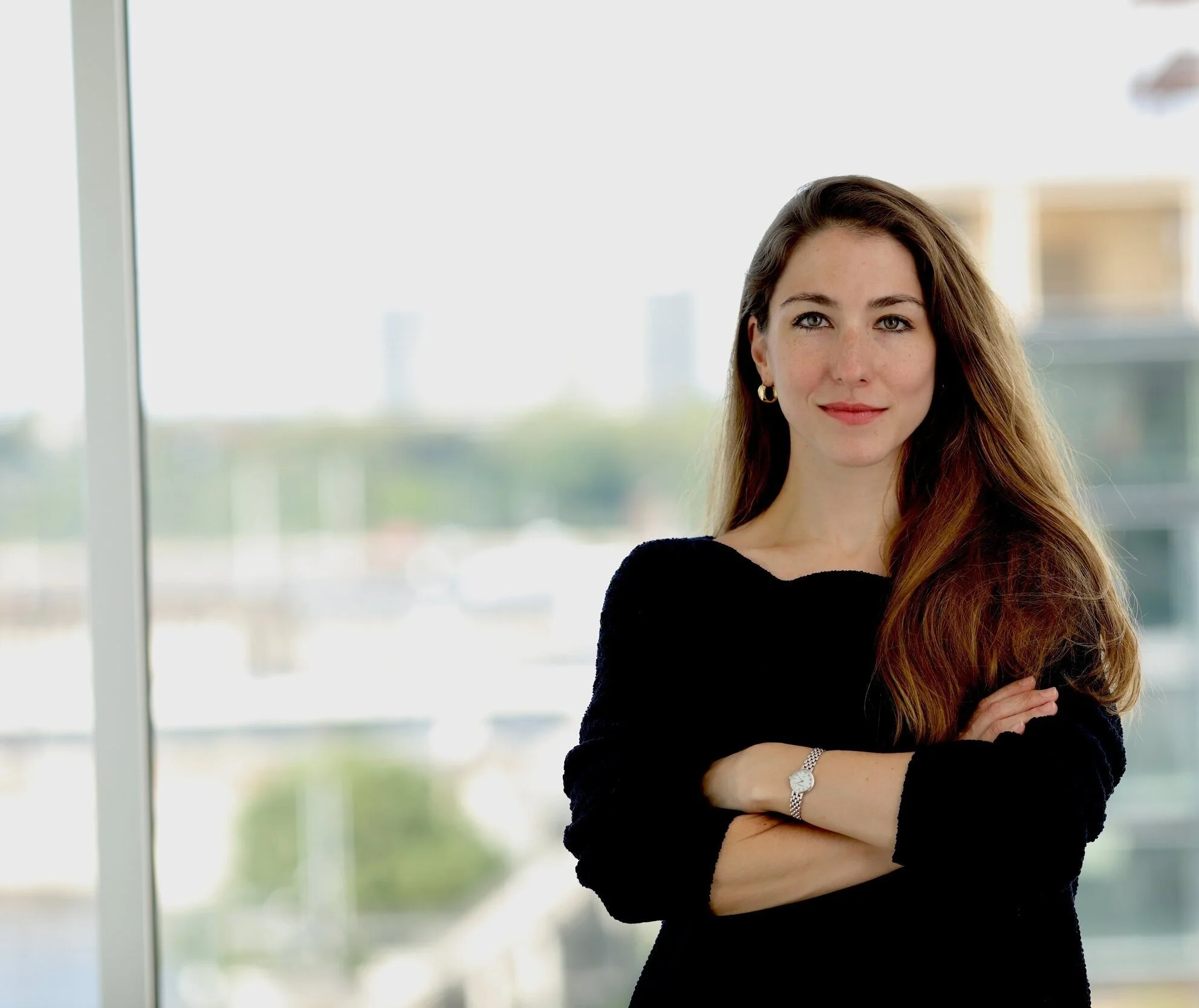 headshot Pilar Casto Di Carlo in front of a glass window with the city blurred behind her