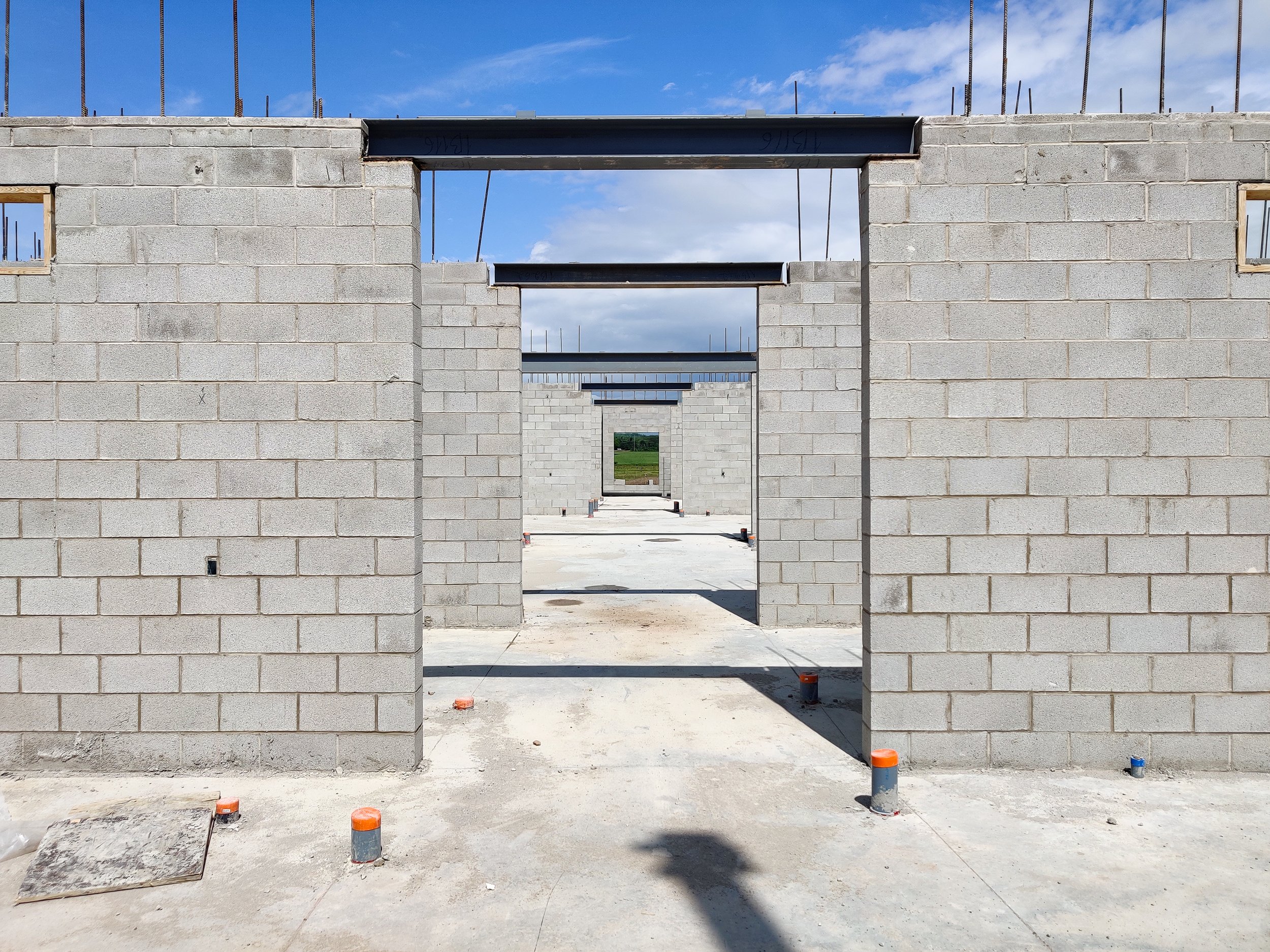 Corridor showing masonry walls with rebar dowels for walls above on each side and steel beams spanning over corridor
