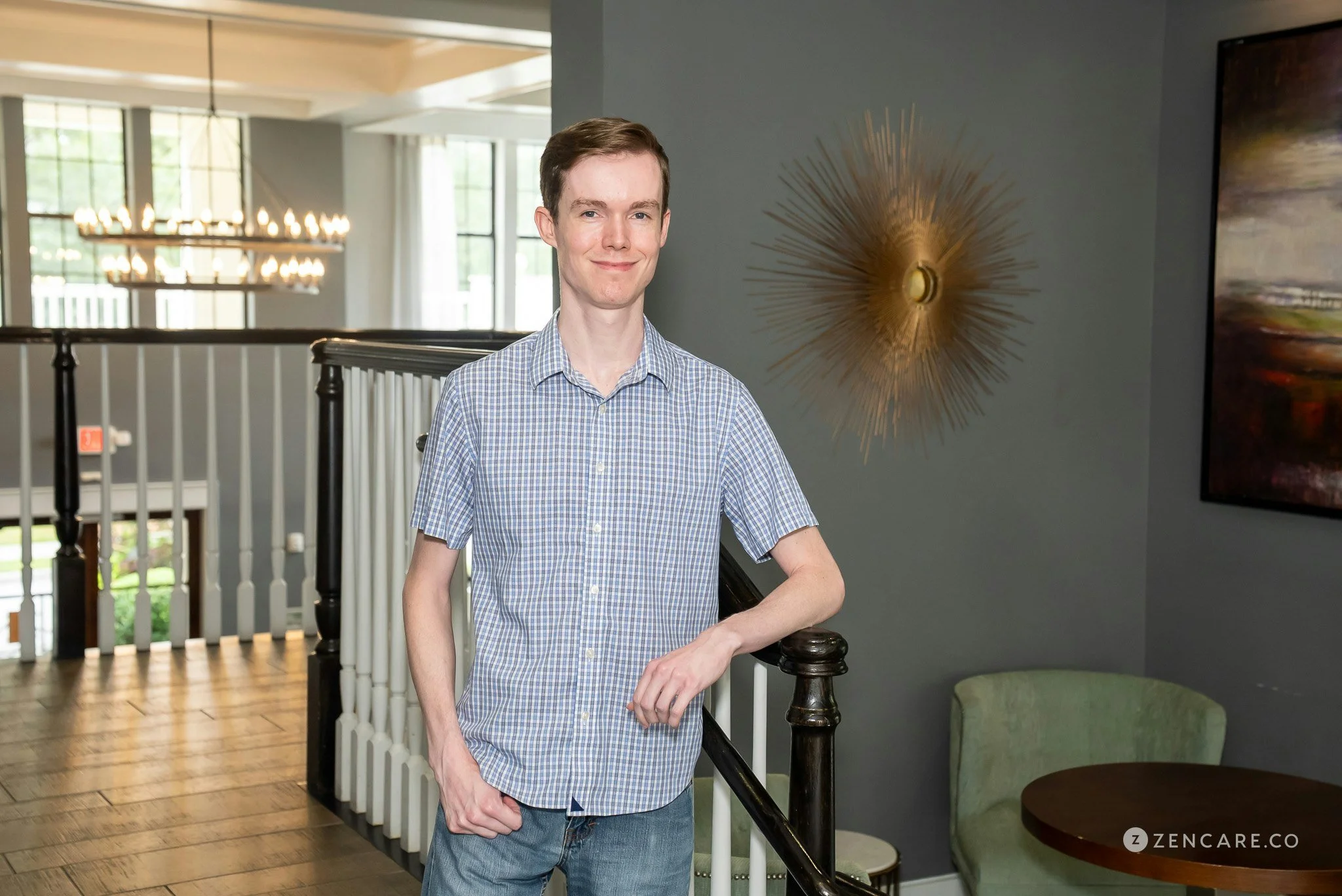 man poses smiling in front of staircase