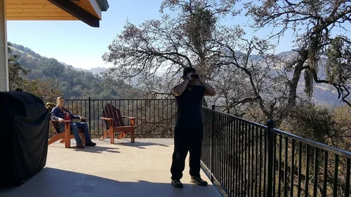Guests relaxing on the Hilltop House balcony at Baxter Ranch, enjoying mountain views with comfortable outdoor seating and scenic forest surroundings.