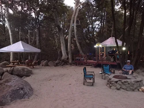 Outdoor fire pit area beside the Creekside Yurt at Baxter Ranch, surrounded by trees and nature, creating a cozy space for relaxing and gathering under the stars.
