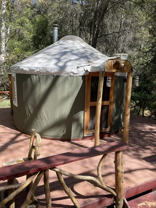 Creekside Yurt at Baxter Ranch, a cozy round retreat nestled among the trees with a private wooden deck and peaceful forest surroundings.