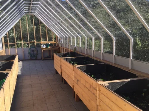 Inside the greenhouse at Baxter Ranch featuring raised garden beds, natural light, and a space dedicated to growing fresh seasonal plants and produce.
