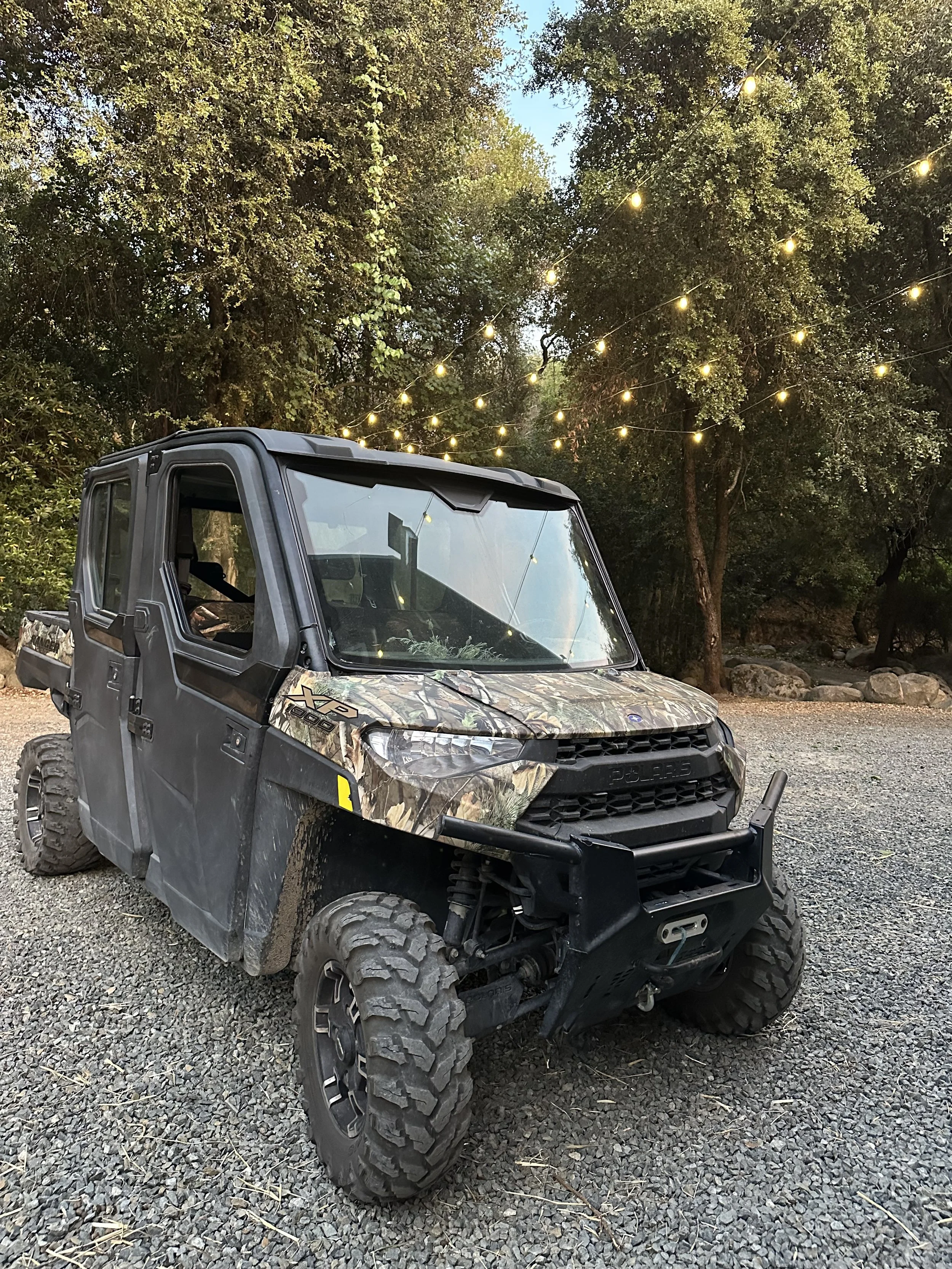 Polaris off-road vehicle at Baxter Ranch parked among trees with outdoor string lights, showcasing the ranch’s rugged mountain setting and outdoor adventure experiences.