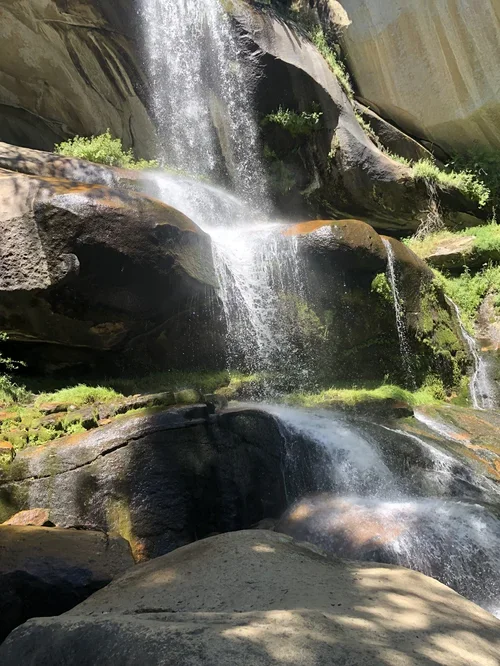 Waterfall cascading over granite rocks near Baxter Ranch, surrounded by lush greenery and the natural beauty of the Sierra Nevada mountain landscape.