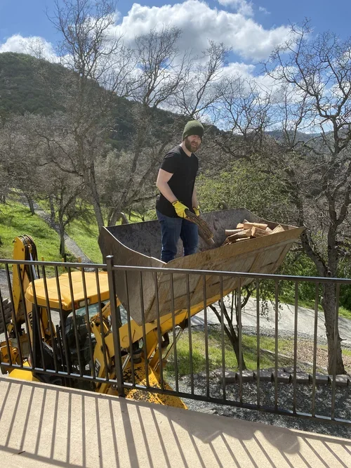 A member of the Baxter Ranch family helping build the property, moving materials during construction while surrounded by the natural mountain landscape and forest.