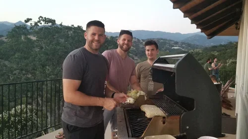 Outdoor dining at Hilltop House, where guests gather around the BBQ at Baxter Ranch to share meals, fresh air, and scenic mountain views from the private patio.

