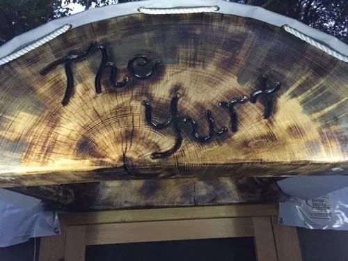 Handcrafted wooden sign marking The Yurt at Baxter Ranch, adding rustic character and a welcoming touch to this unique creekside mountain retreat.