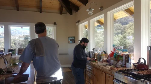 Guests preparing food together in the Hilltop House kitchen at Baxter Ranch, featuring a spacious layout, natural light, and mountain retreat atmosphere.
