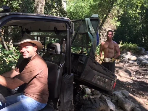 Baxter Ranch family members working during the construction of the property near the year-round creek, surrounded by rocks, trees, and the natural mountain landscape.