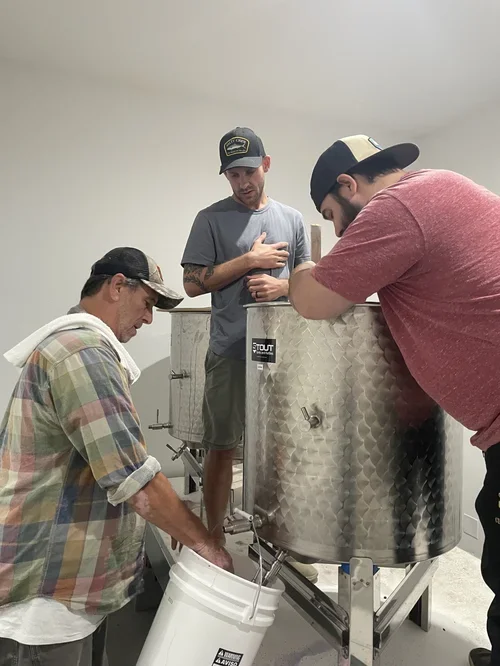 Baxter Ranch winemaking process with a small team working around stainless steel equipment, showcasing the hands-on craftsmanship behind the vineyard harvest and handcrafted wine production.