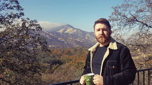 Guest enjoying a quiet moment outdoors at Baxter Ranch with a warm drink, surrounded by forest, mountain views, and the peaceful beauty of the ranch setting.