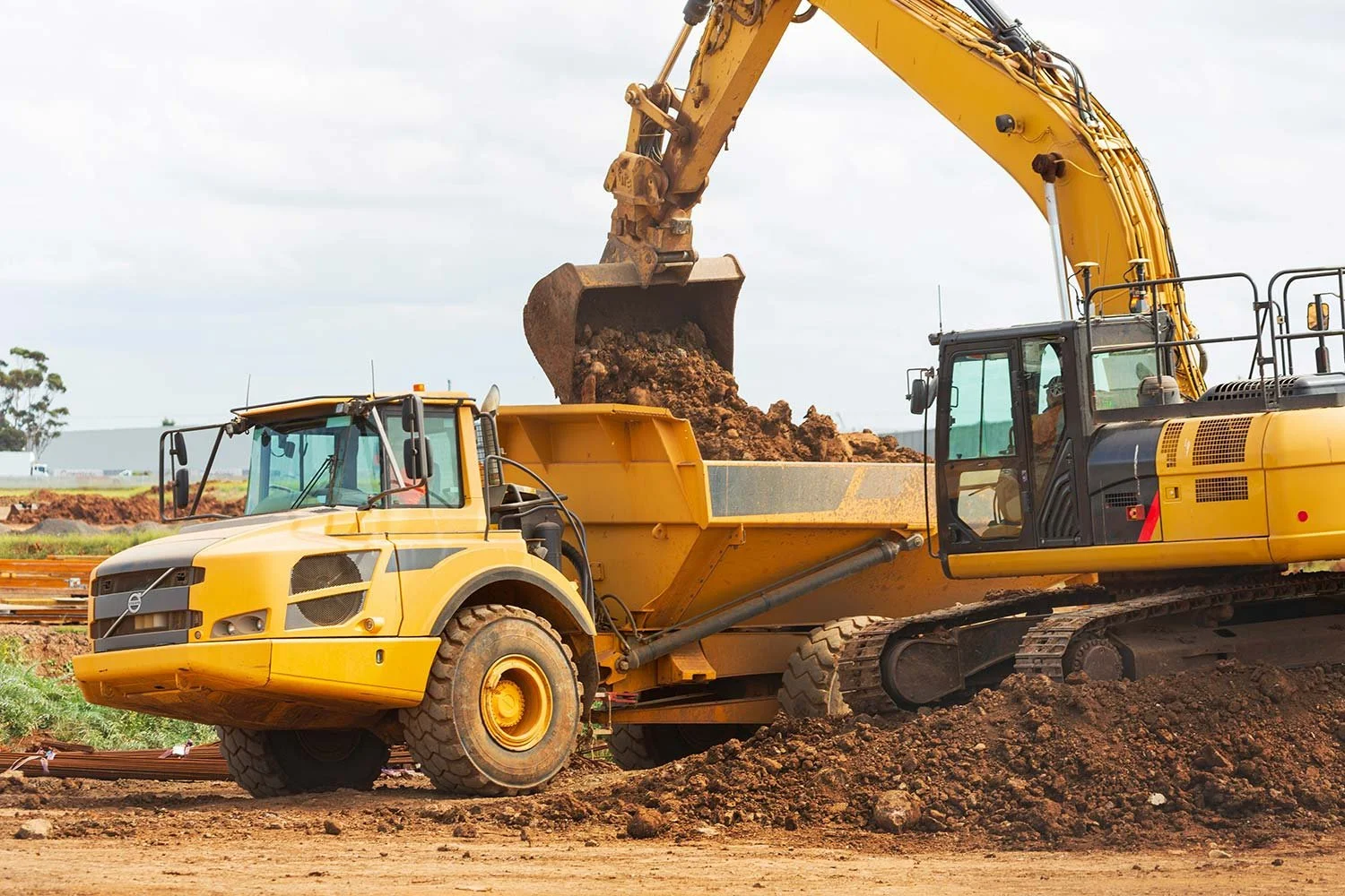 Excavator loading soil into a dump truck