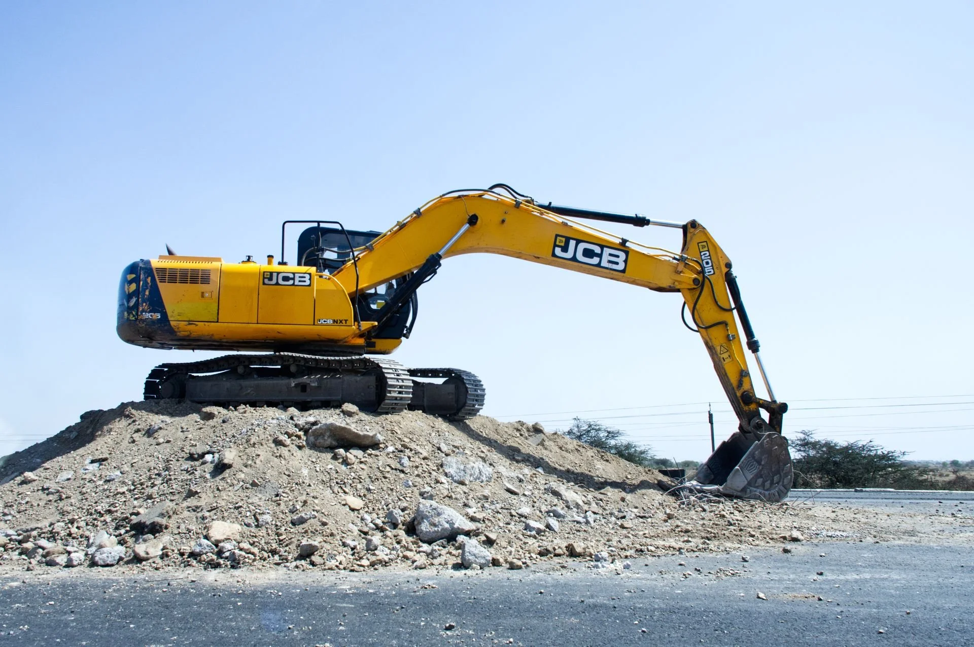 Yellow JCB excavator moving dirt on a commercial site