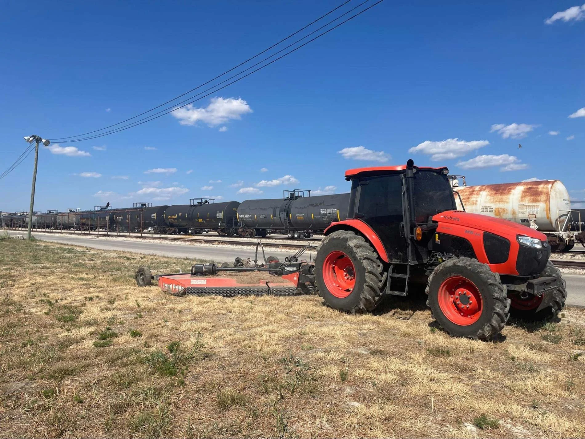 Tractor and backhoe performing right-of-way maintenance work on rural land