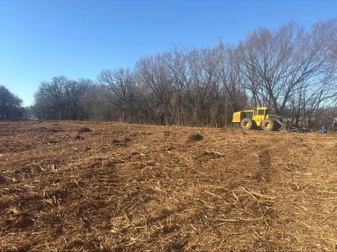 Excavator removing tree roots and brush for right-of-way maintenance