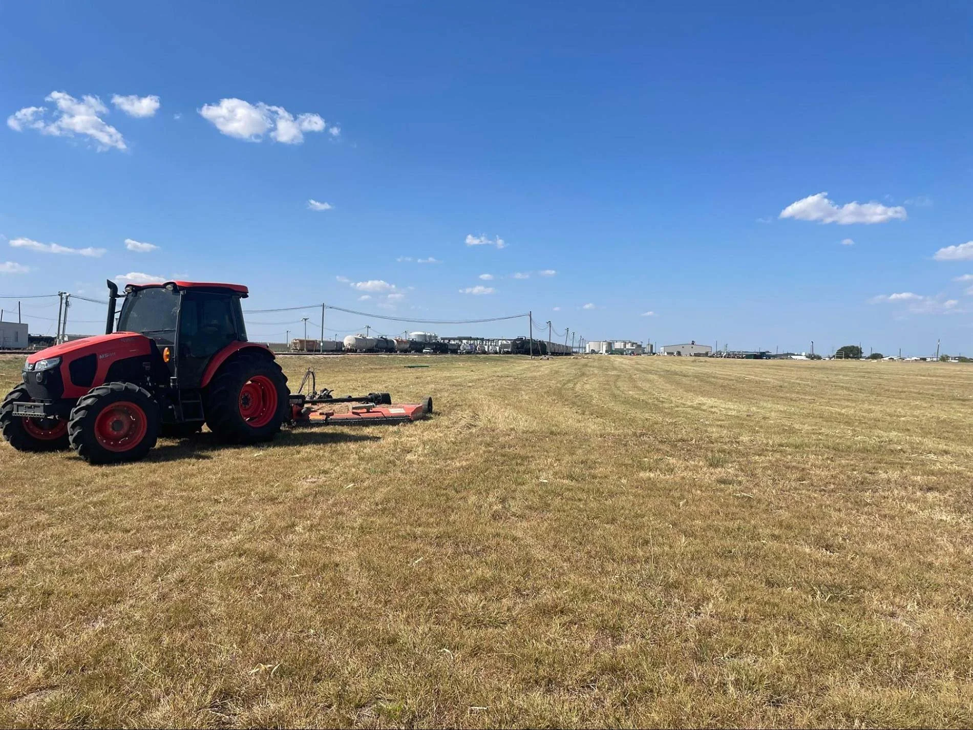 Blue tractor mowing a large grassy pasture in Texas