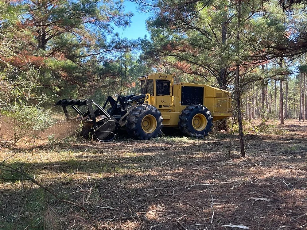 A yellow mulcher clearing brush