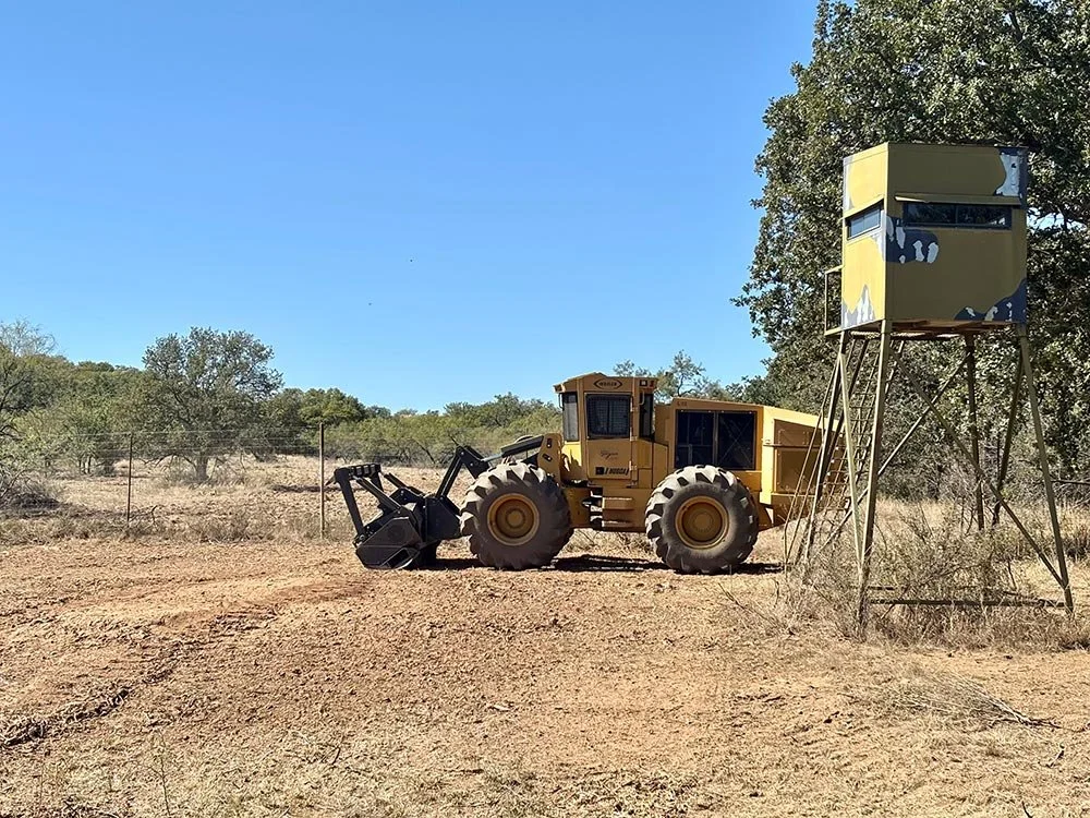 Yellow land-clearing equipment next to a hunting blind