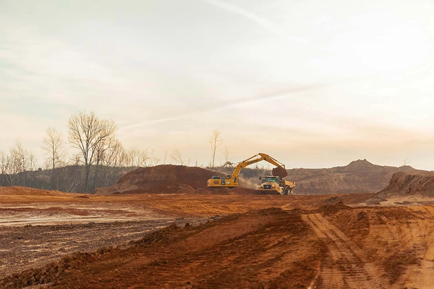 Excavator loading a dump truck at a pipeline site