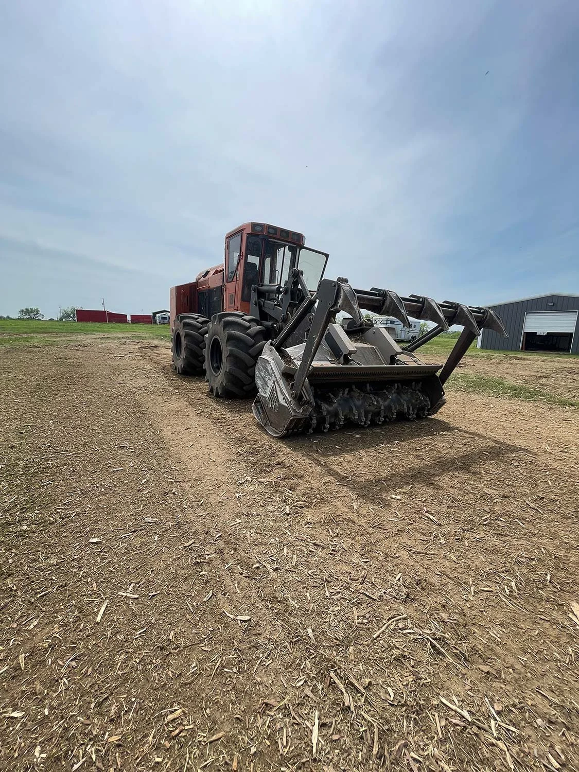 A red mulcher sits atop recently cleared and leveled rural land