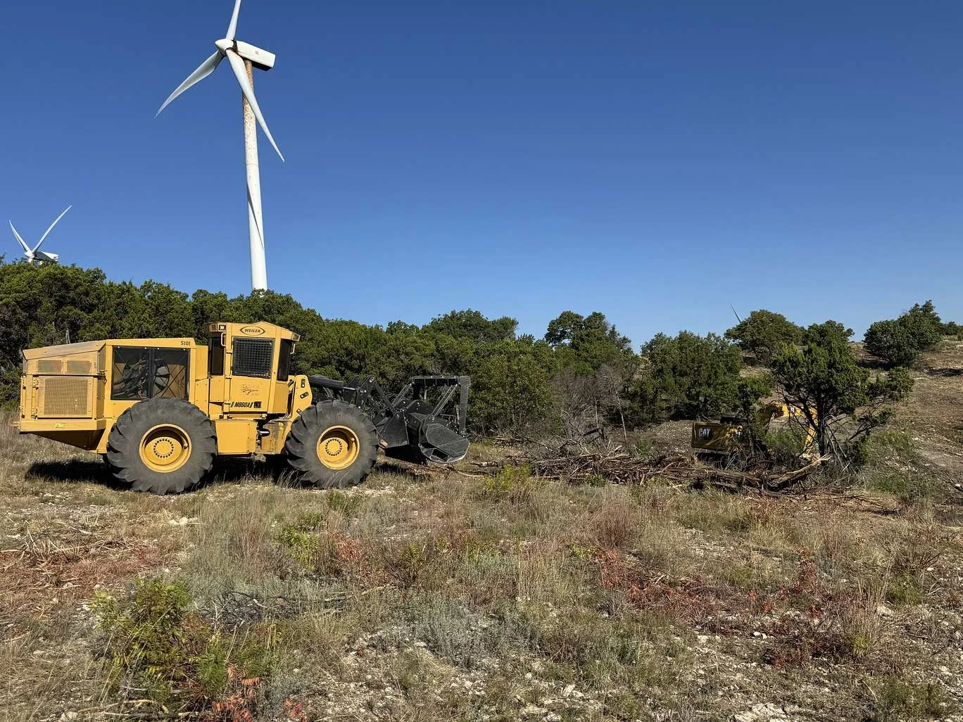 Land clearing equipment on a rural site near wind turbines