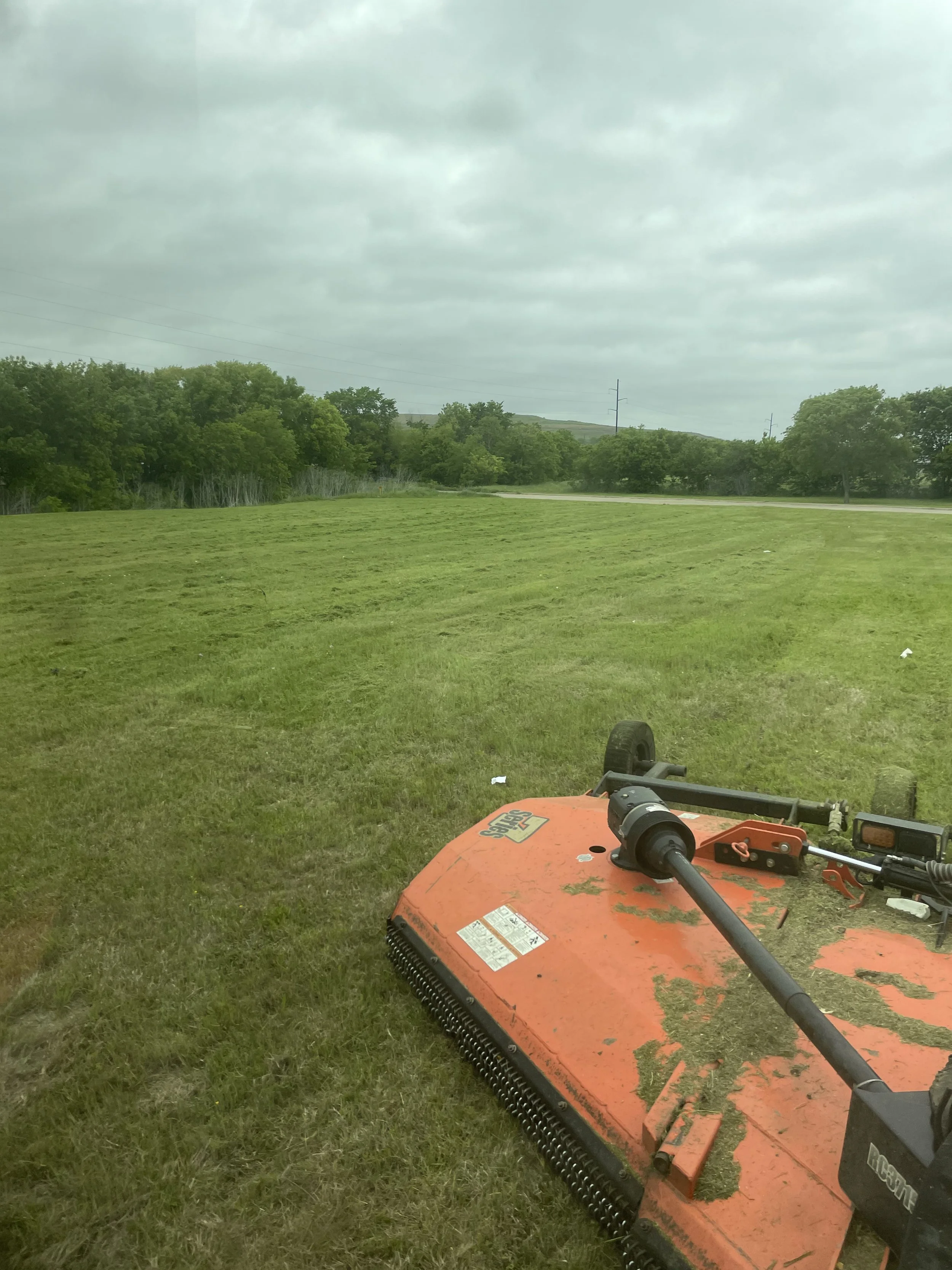 Red tractor mowing on grass field