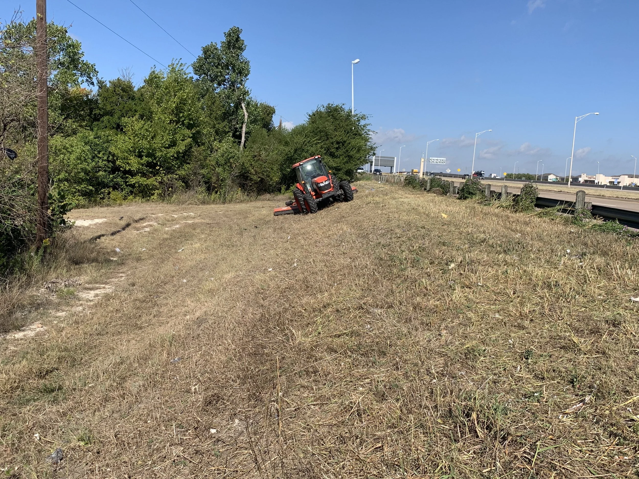Tractor mowing on hill beside road