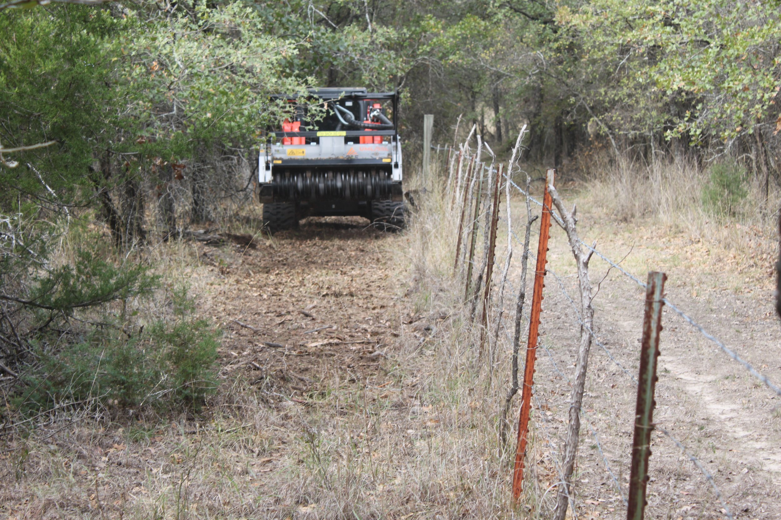 Skid-steer moving along fence line
