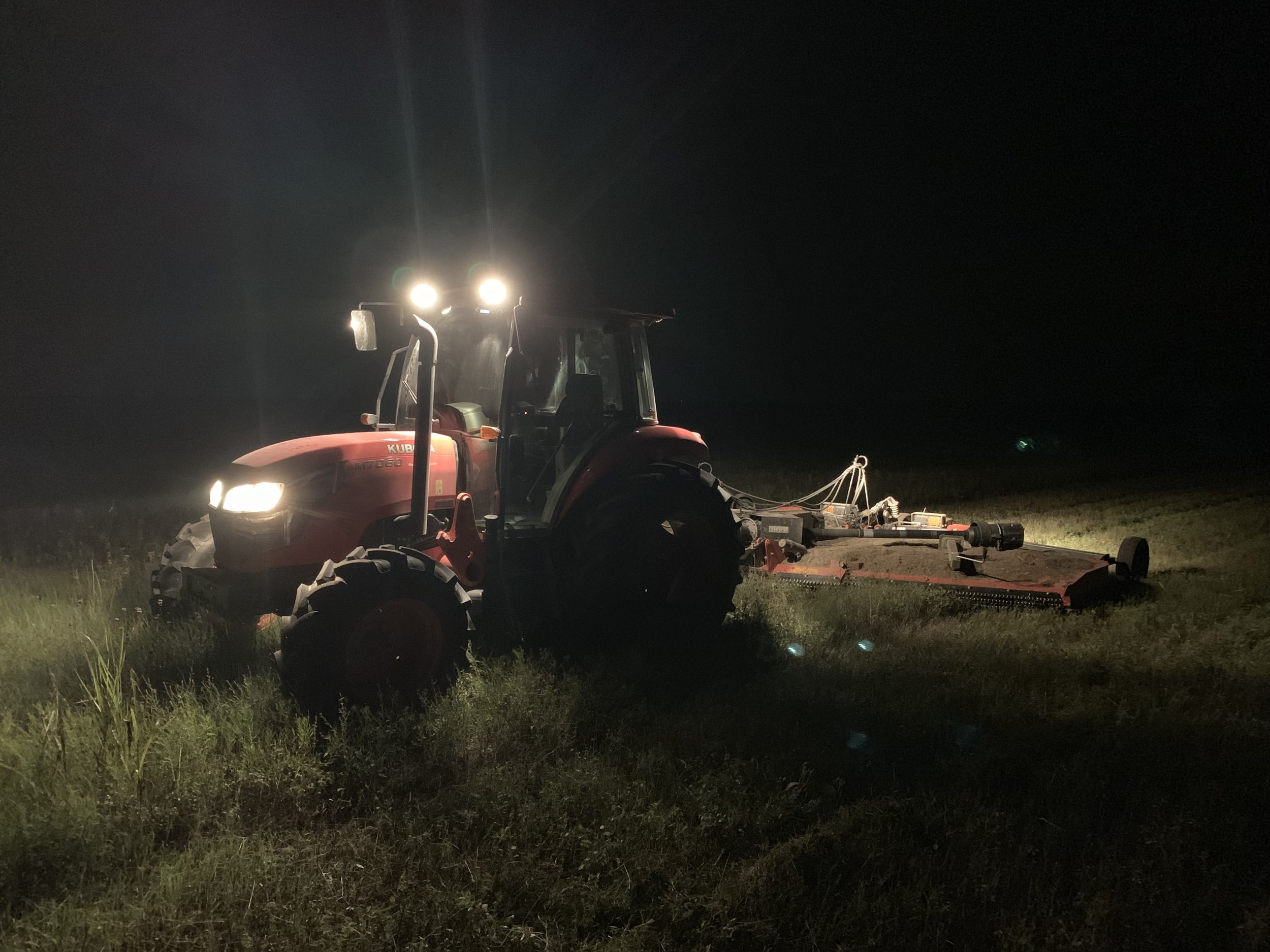 Red Tractor with headlights on at night