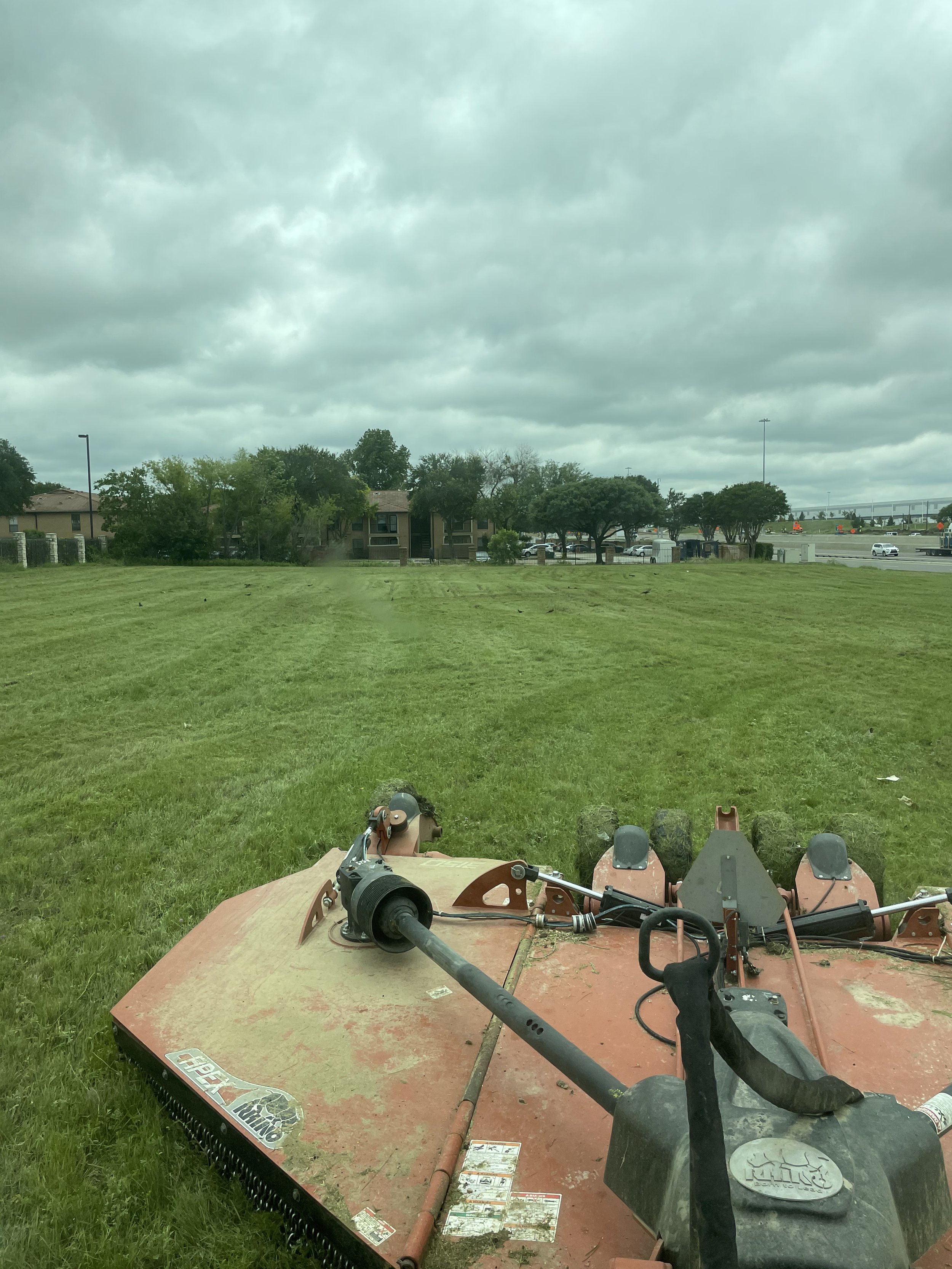 Red tractor mowing grass field