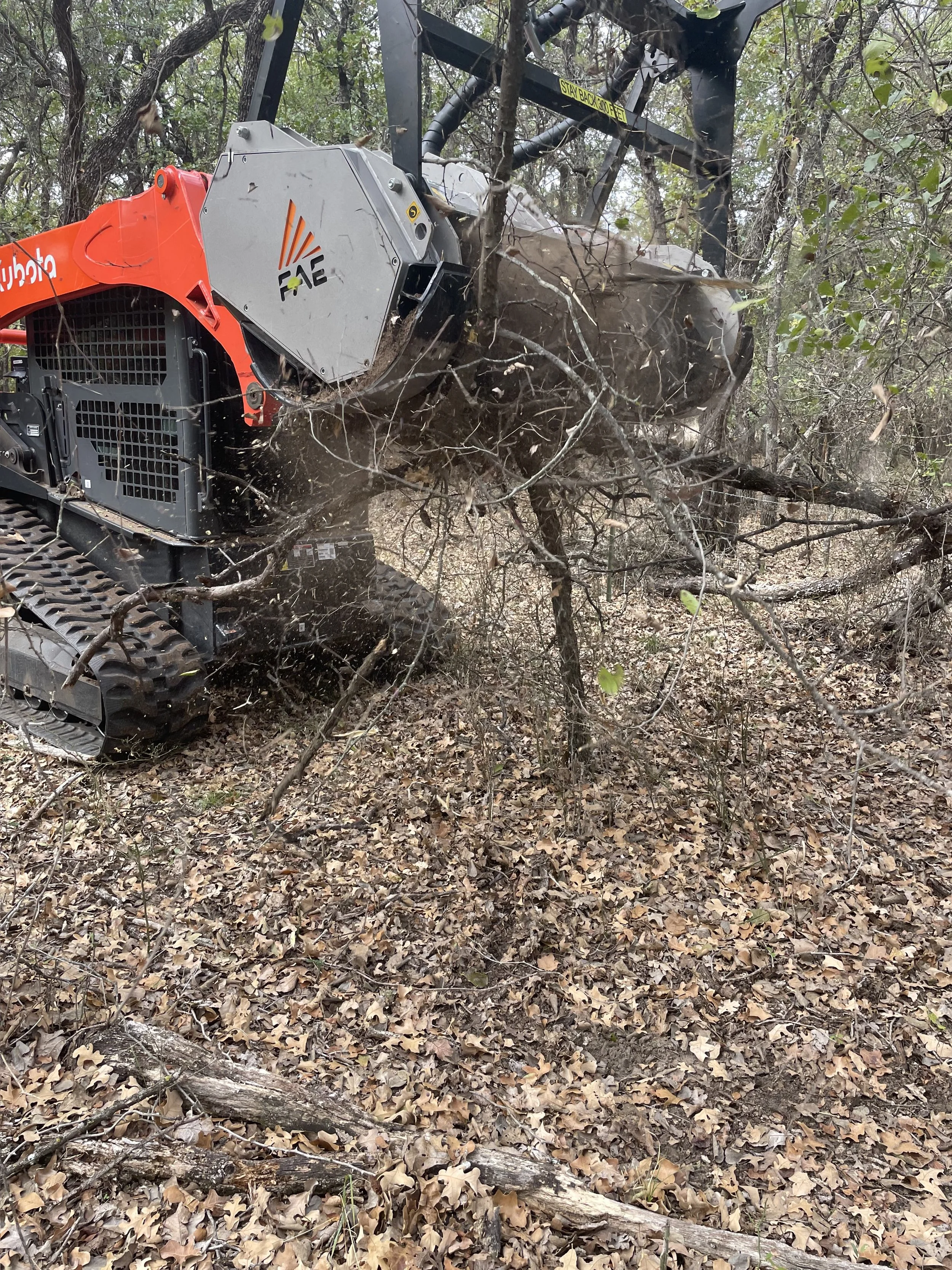 Skid-steer cutting down branches