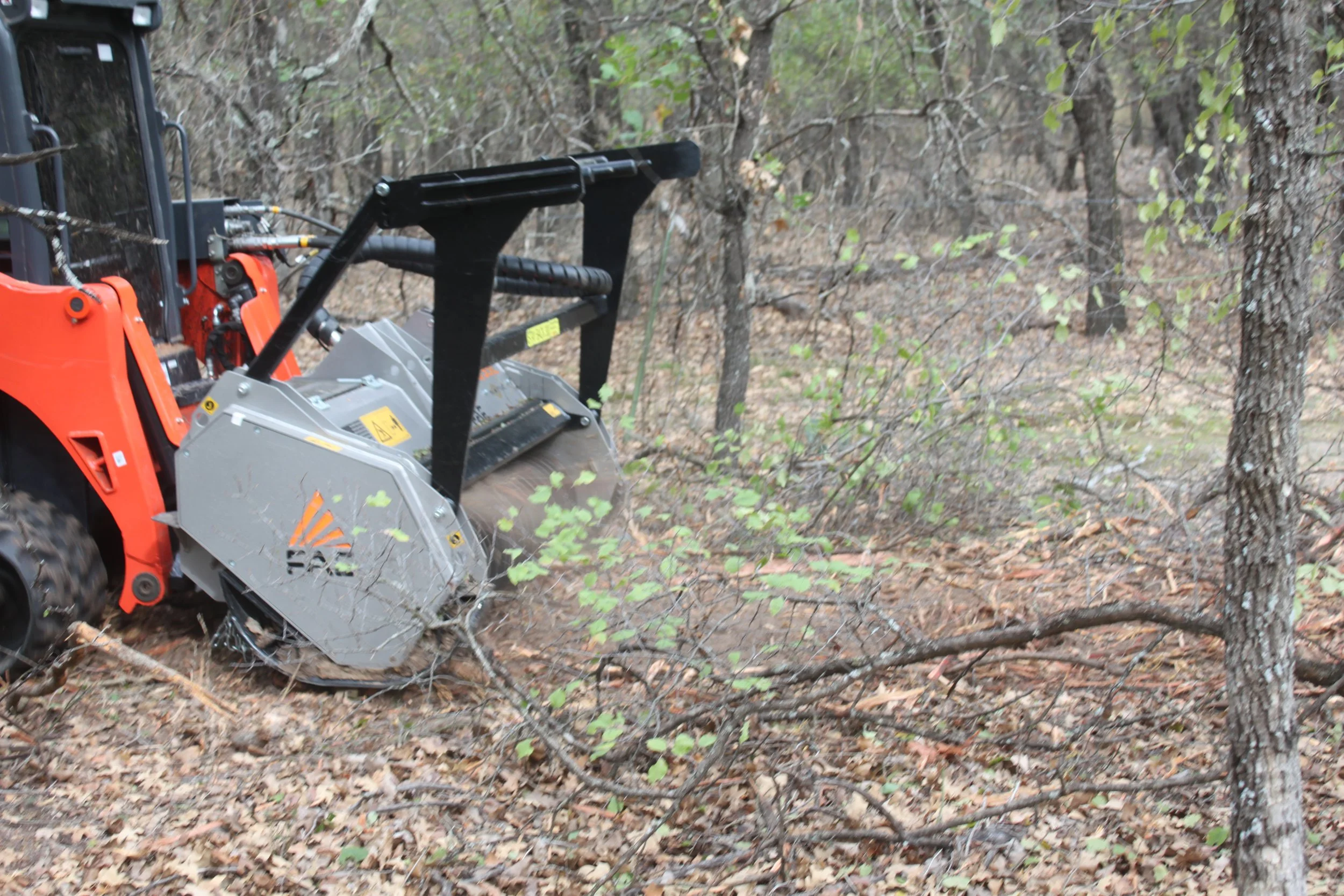 Skid-steer mowing through trees