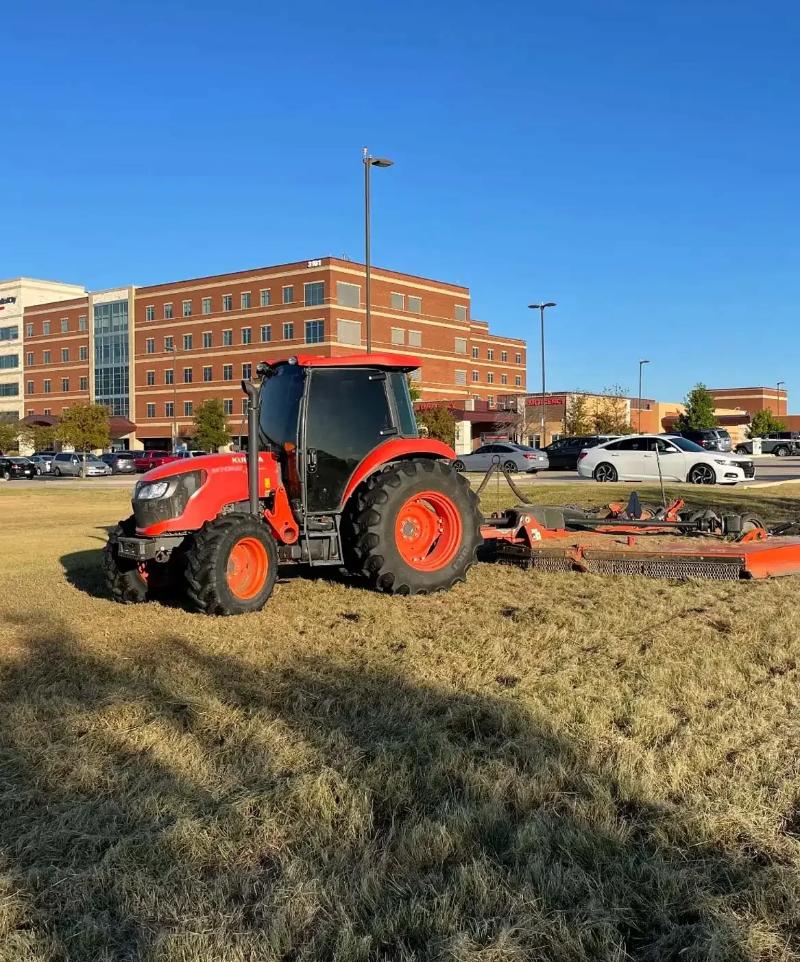 Red tractor mowing through field