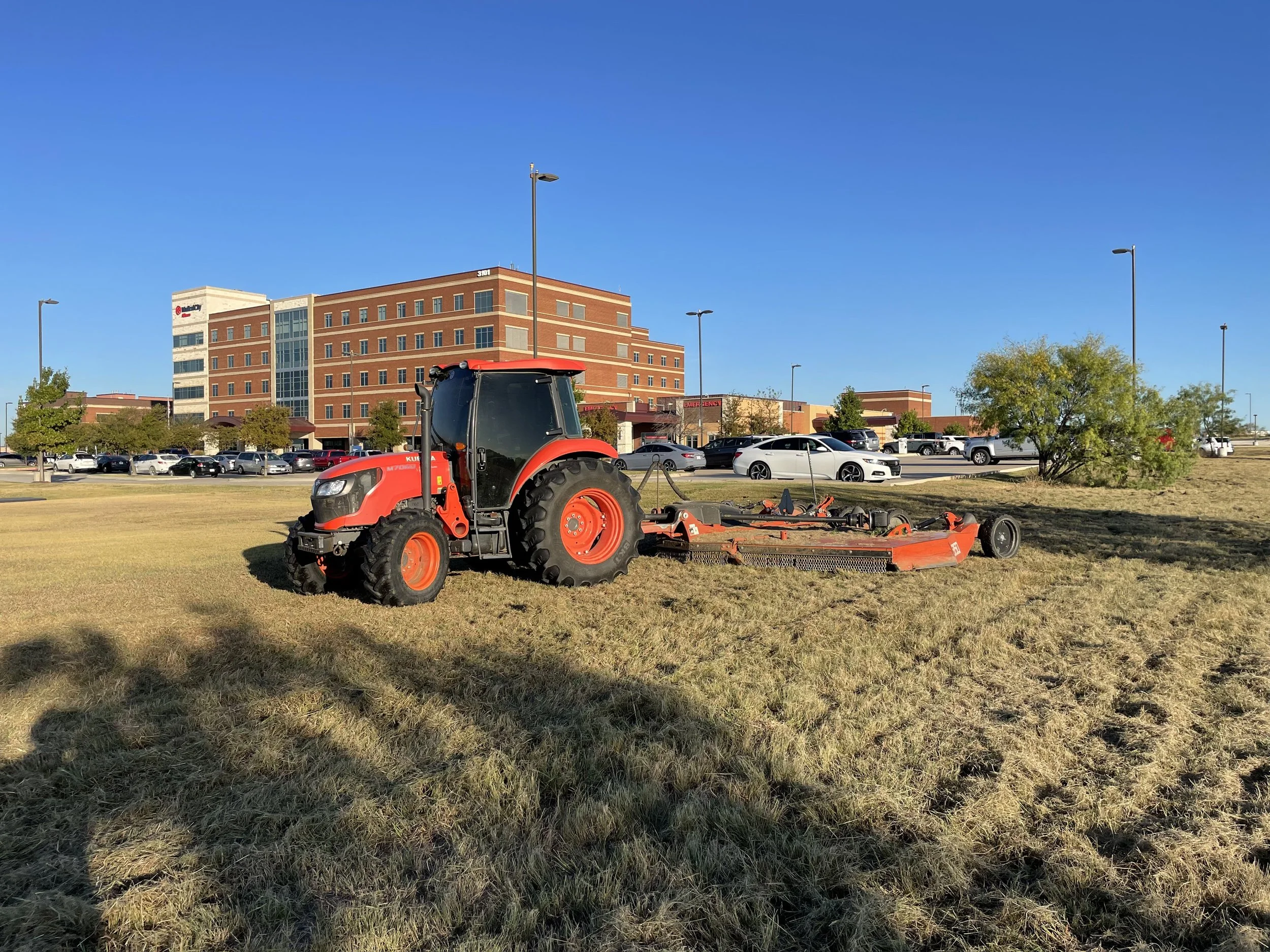 Red tractor mowing through a yellow field