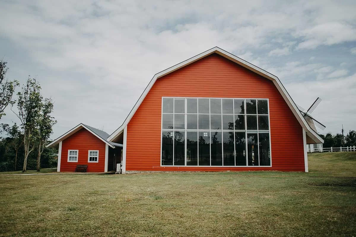 Red barndominium with large windows on rural property