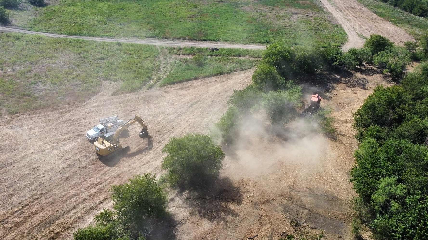 A top-down view of various land clearing machinery and work vehicles clearing a tract of land