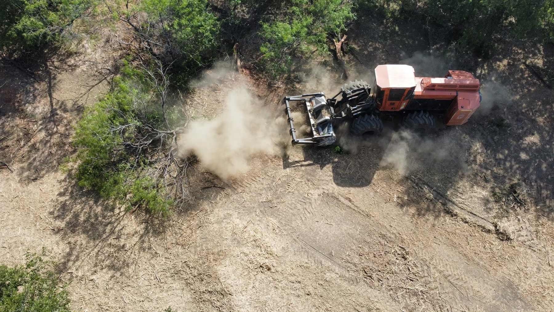 A top-down view of red land clearing machinery in operation