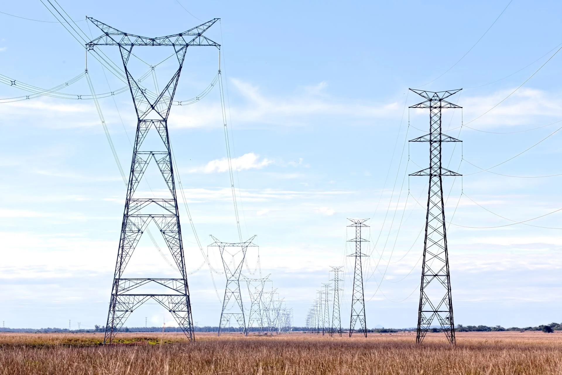 High voltage transmission towers and power lines crossing a rural field